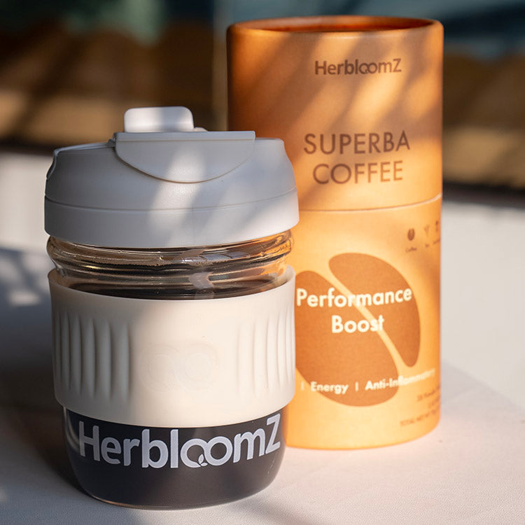 HerbloomZ Wellness Cup filled with coffee beside SUPERBA COFFEE Performance Boost canister, styled in soft natural lighting for an energizing ritual vibe. - HerbloomZ