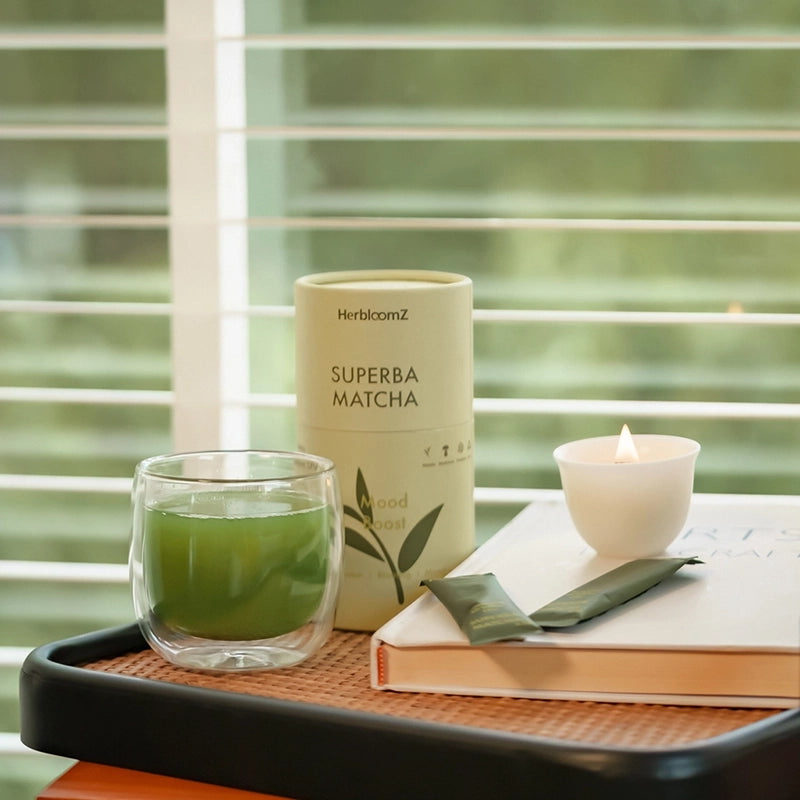 Superba Matcha container with a glass of probiotic matcha and a candle on a tray.