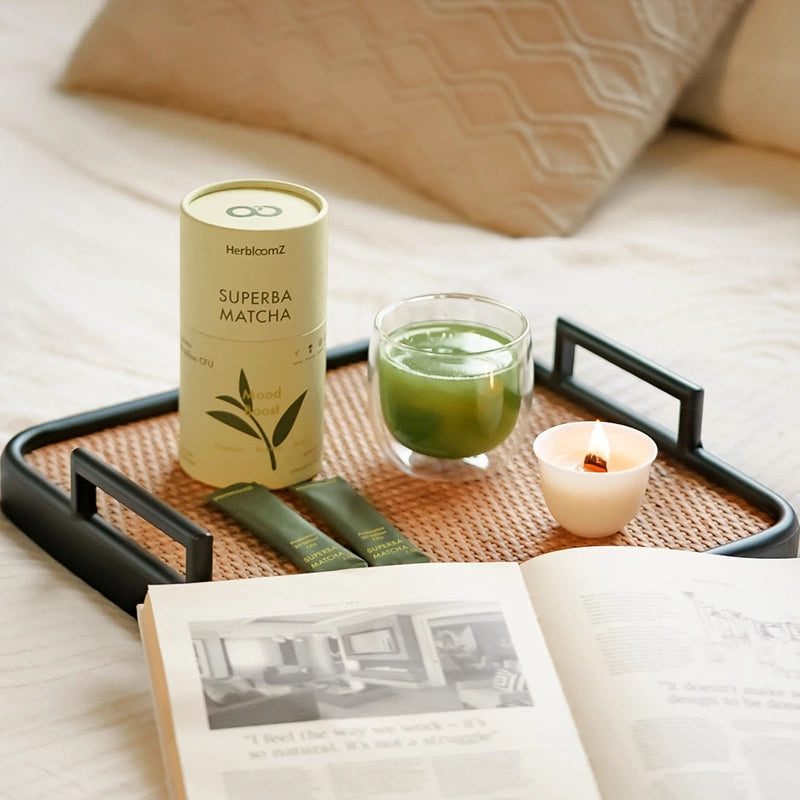 A calming morning ritual featuring the HerbloomZ SUPERBA MATCHA SET, with a prepared cup of probiotic matcha, bamboo zen candle, and single-serving packets on a tray