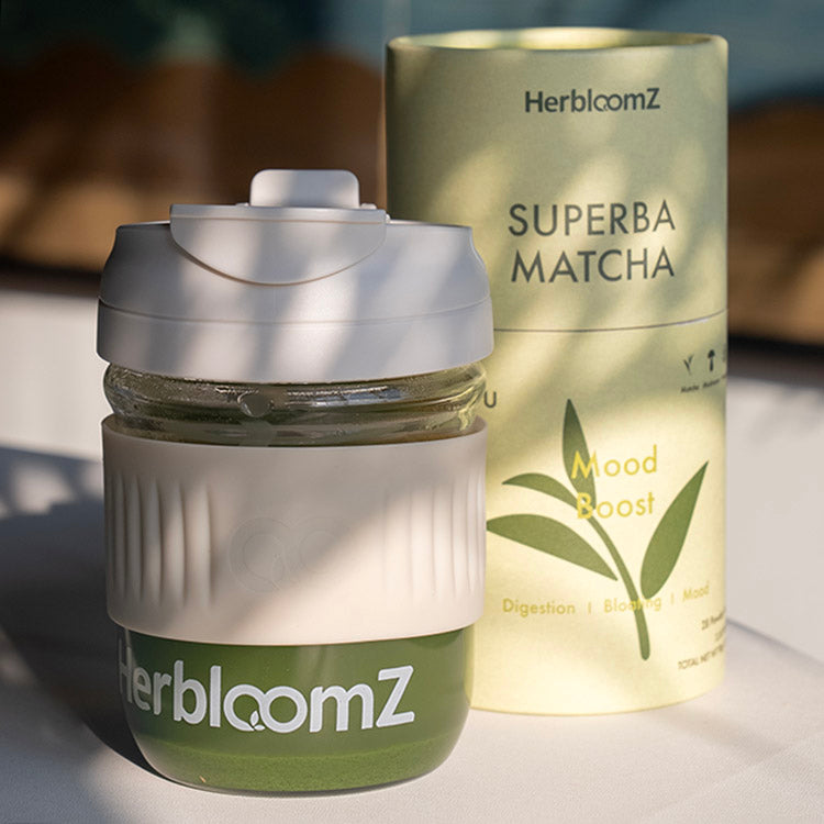 HerbloomZ Wellness Cup filled with matcha next to SUPERBA MATCHA Mood Boost canister, captured in natural sunlight for a calming ritual vibe. - HerbloomZ