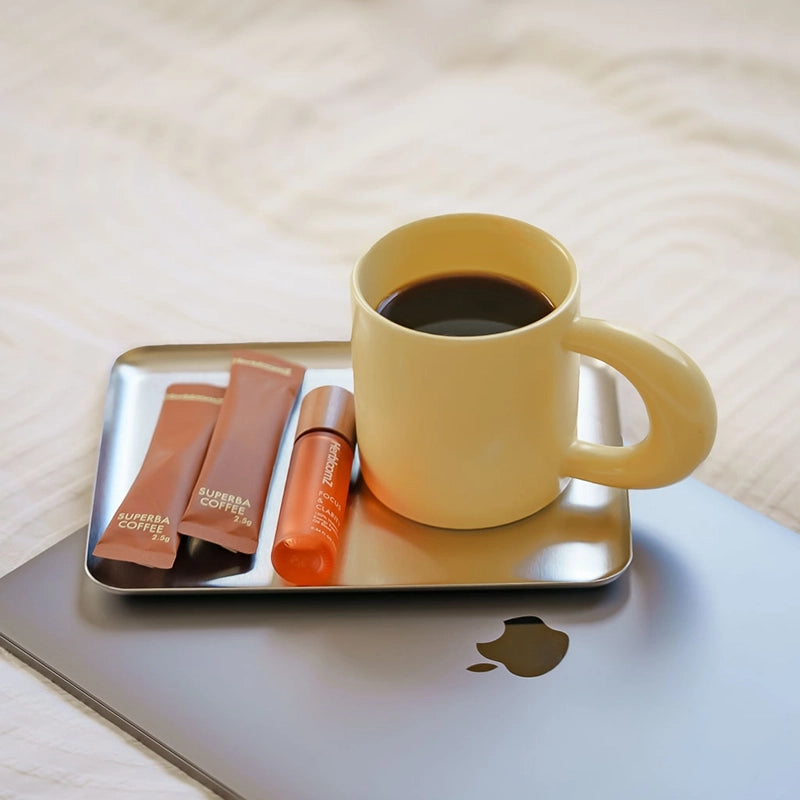 HerbloomZ SUPERBA Coffee mushroom coffee sachets with oolong tea and Focus Essential Oil beside a yellow mug on laptop, calm focus ritual