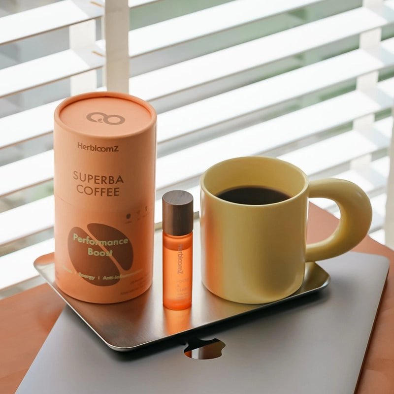 Herbloomz SUPERBA mushroom coffee with oolong tea on a work desk beside laptop and Focus Essential Oil, gut-friendly energy for focus