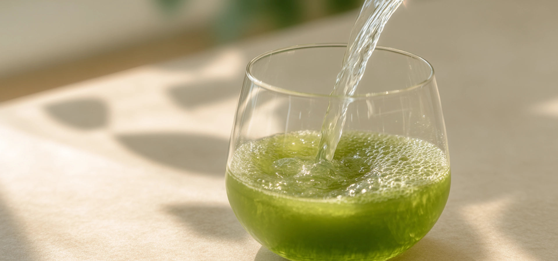 A glass of probiotic matcha tea being poured, HerbloomZ stress relief tea that helps reduce cortisol, ease stress, and improve focus