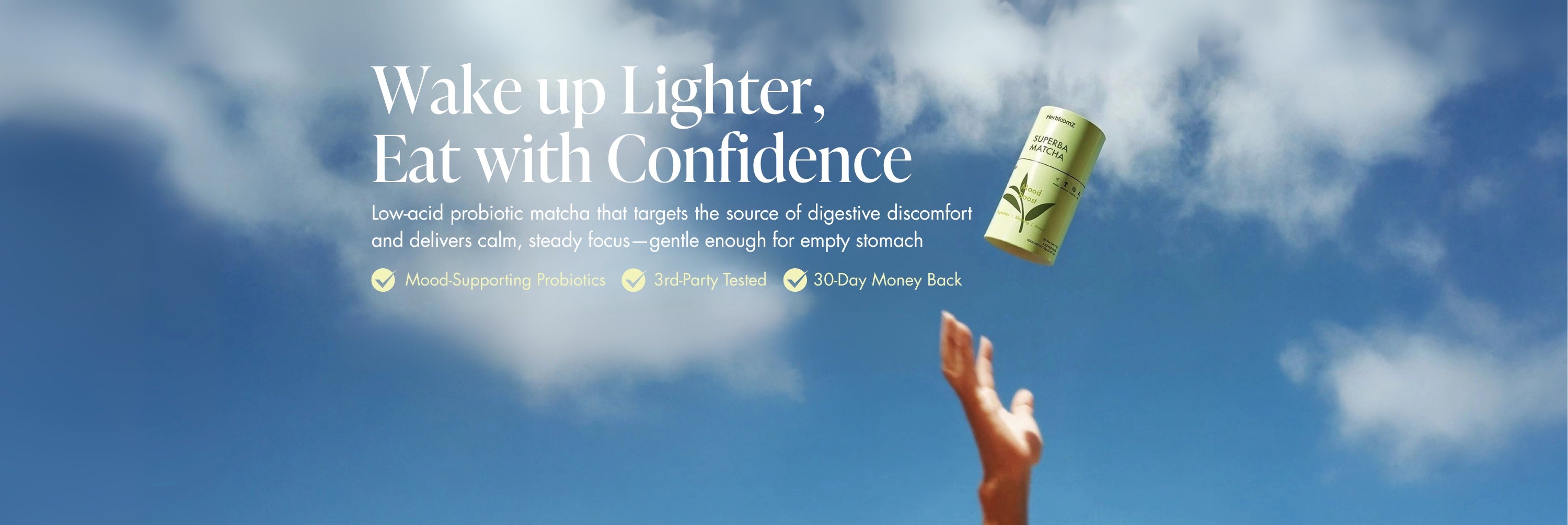 Hand reaching for a herbloomz probiotic matcha container against a blue sky with promotional text